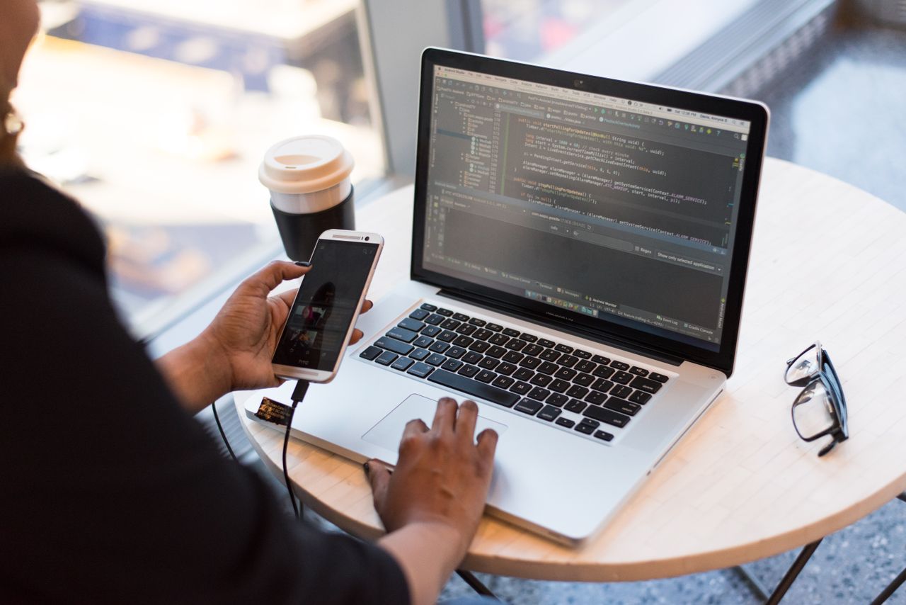 A learner working with a smartphone and laptop