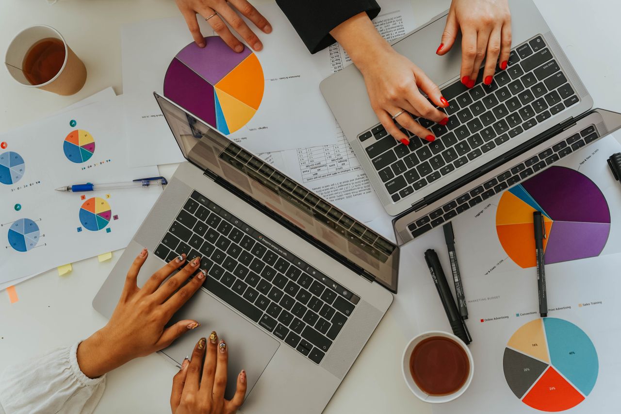 People collaborating with laptops and printed charts