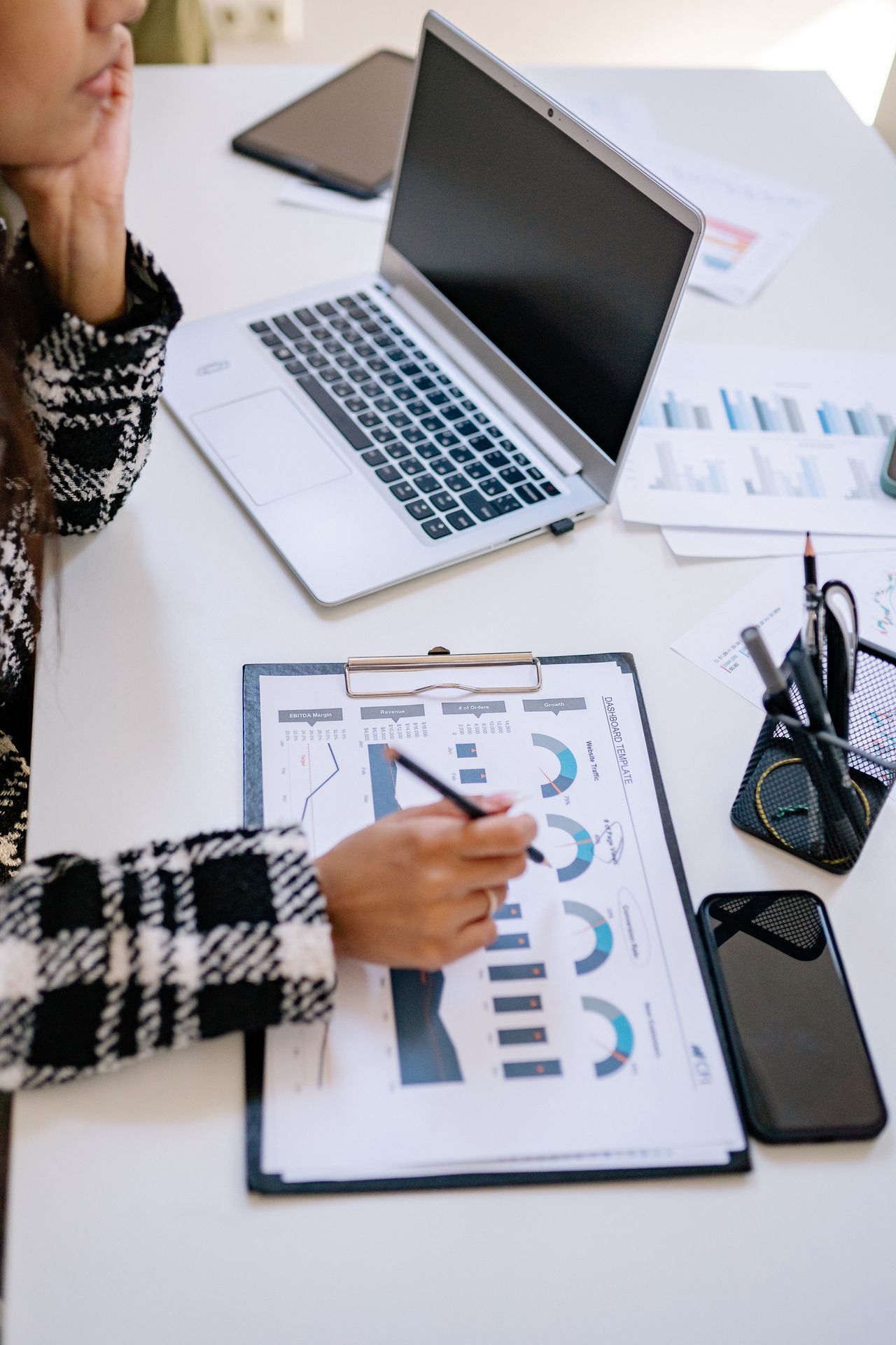 A person comparing charts and business reports at a desk