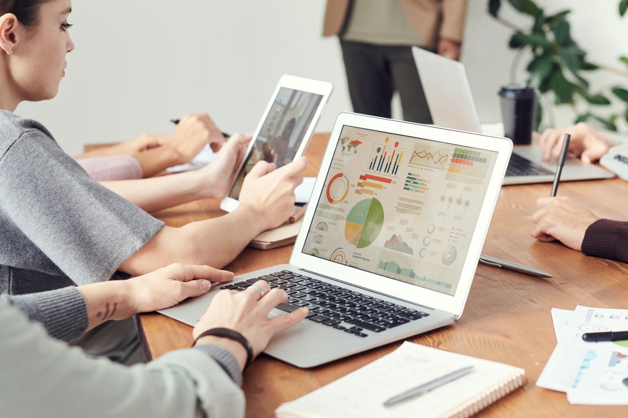 A group reviewing charts and information on laptop screens