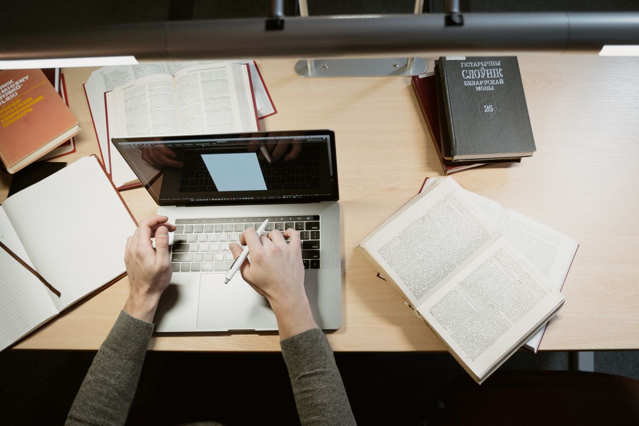 A student researching and typing at a library desk
