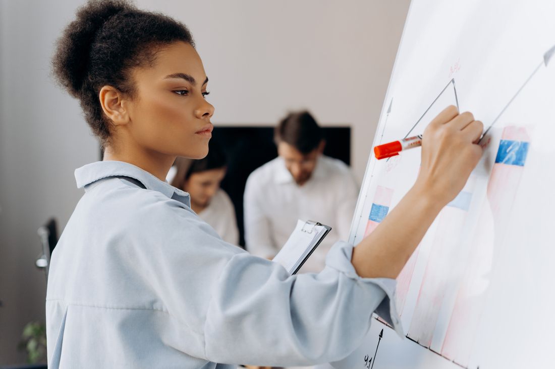 A professional writing ideas on a whiteboard with colleagues